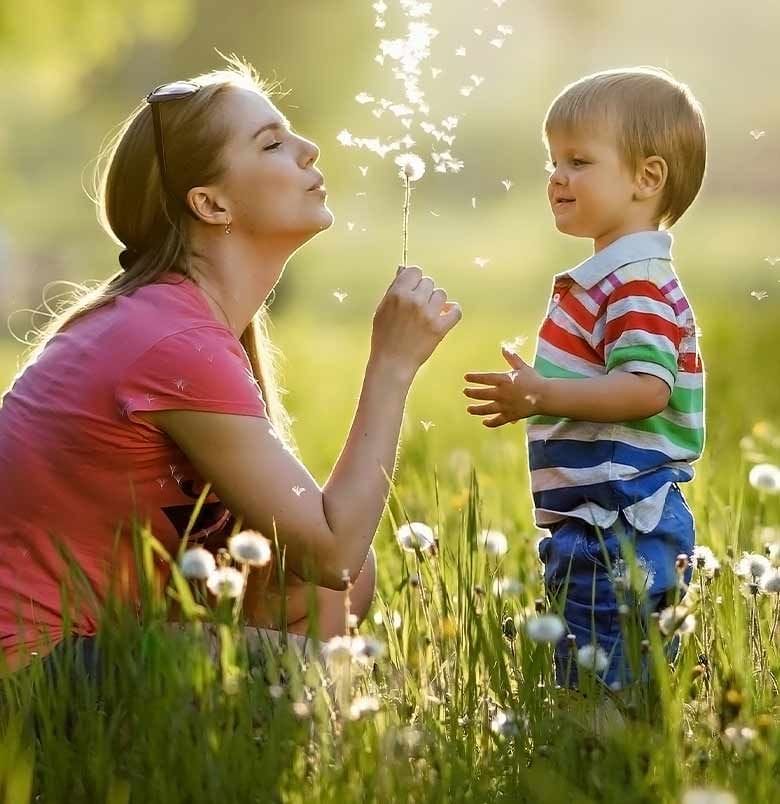 Nounou fait des bulles dans un parc avec un petit garçon