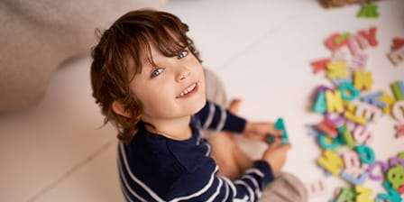 Petit garçon souriant jouant avec des lettres en mousse