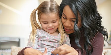 Nounou tenant dans ses bras une petite fille attentive