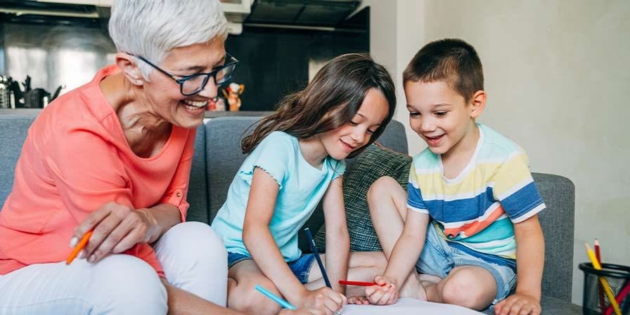 Nounou retraitée qui fait du coloriage avec 2 enfants