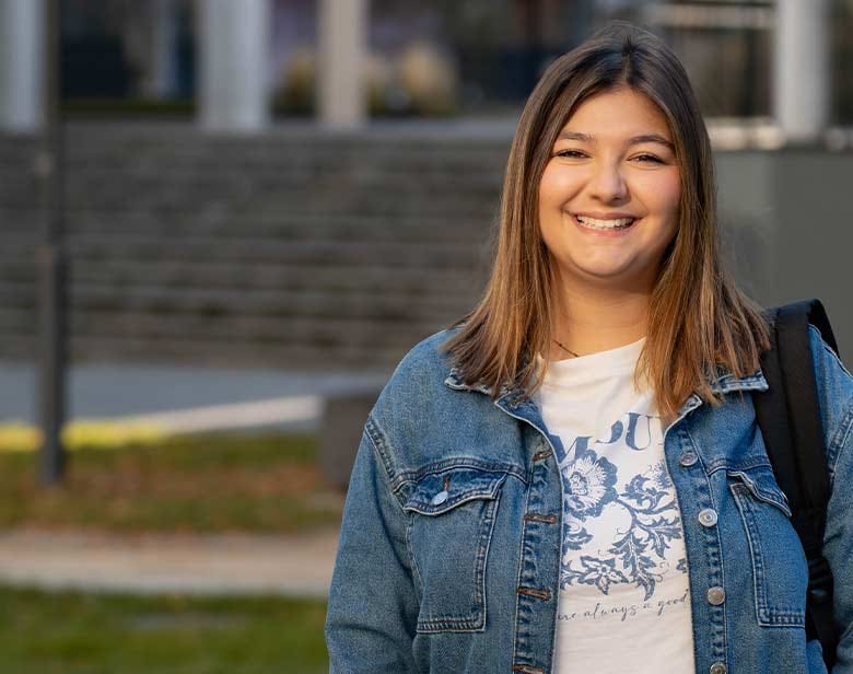 Nounou étudiante souriant devant une université,