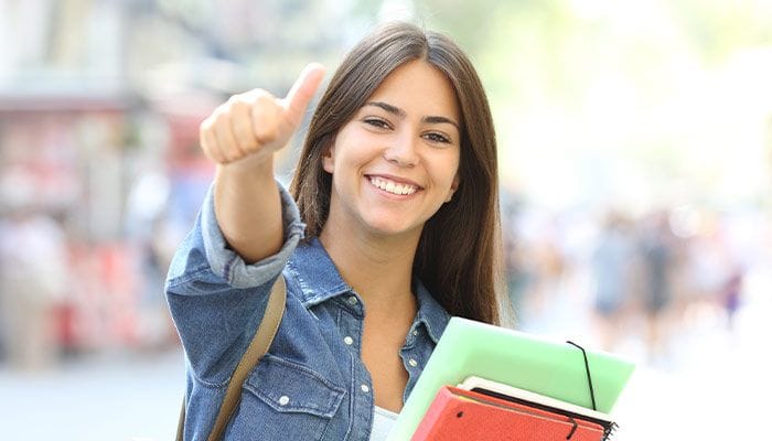 Nounou étudiante sortant de la fac faisant un pouce levé à la caméra