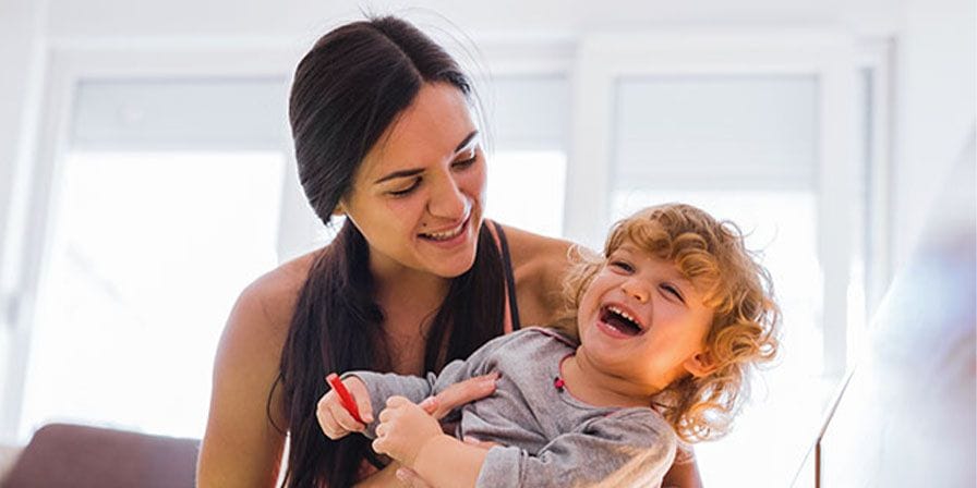 Nounou qui porte et joue avec un enfant 