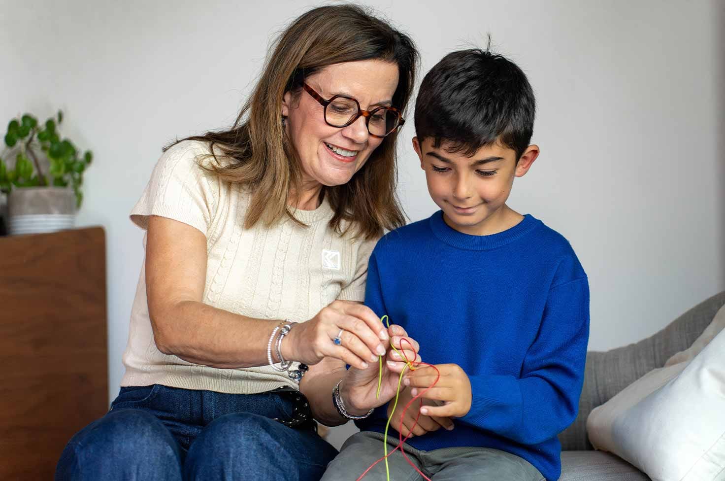 Nounou montrant à un garçon comment faire un bracelet tressé