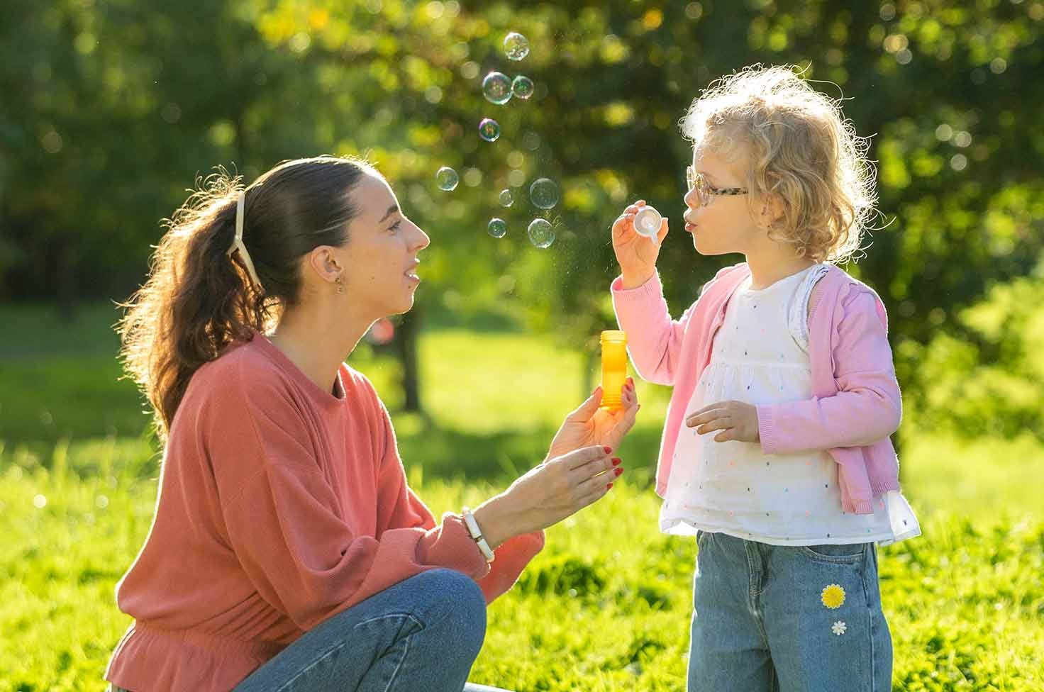 Nounou regardant une petite fille faire des bulles par un mercredi ensoleillé