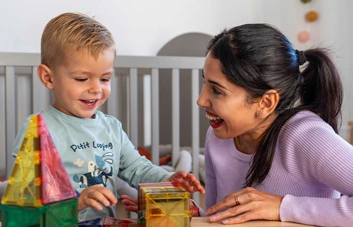 Nounou et petit garçon riant autour d'une activité d'éveil