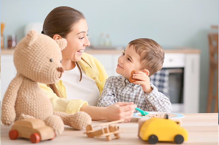 Nounou en train de donner à manger à un petit garçon attentif