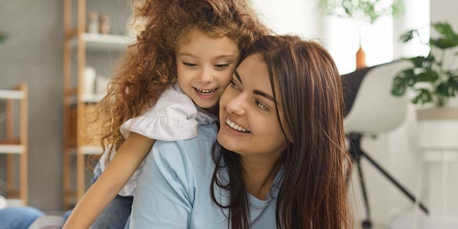 Nounou étudiante qui sourit à une petite fille dans le salon