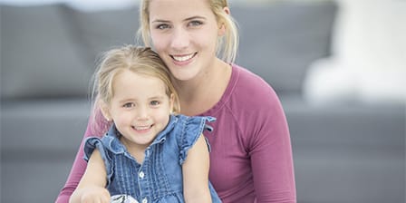 Nounou tenant un petite fille sur ses genoux devant un canapé
