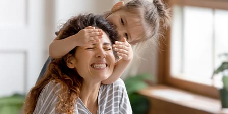 Nounou jouant avec une petite fille qui lui cache les yeux