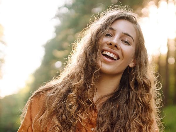 Jeune nounou étudiante souriant à la caméra dans un parc