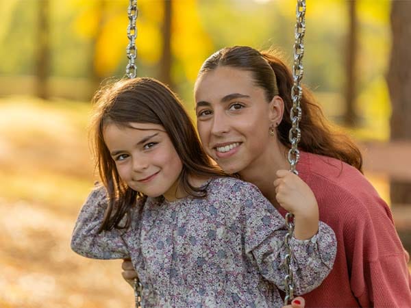 Petite fille sur une balançoire accompagnée de sa nounou